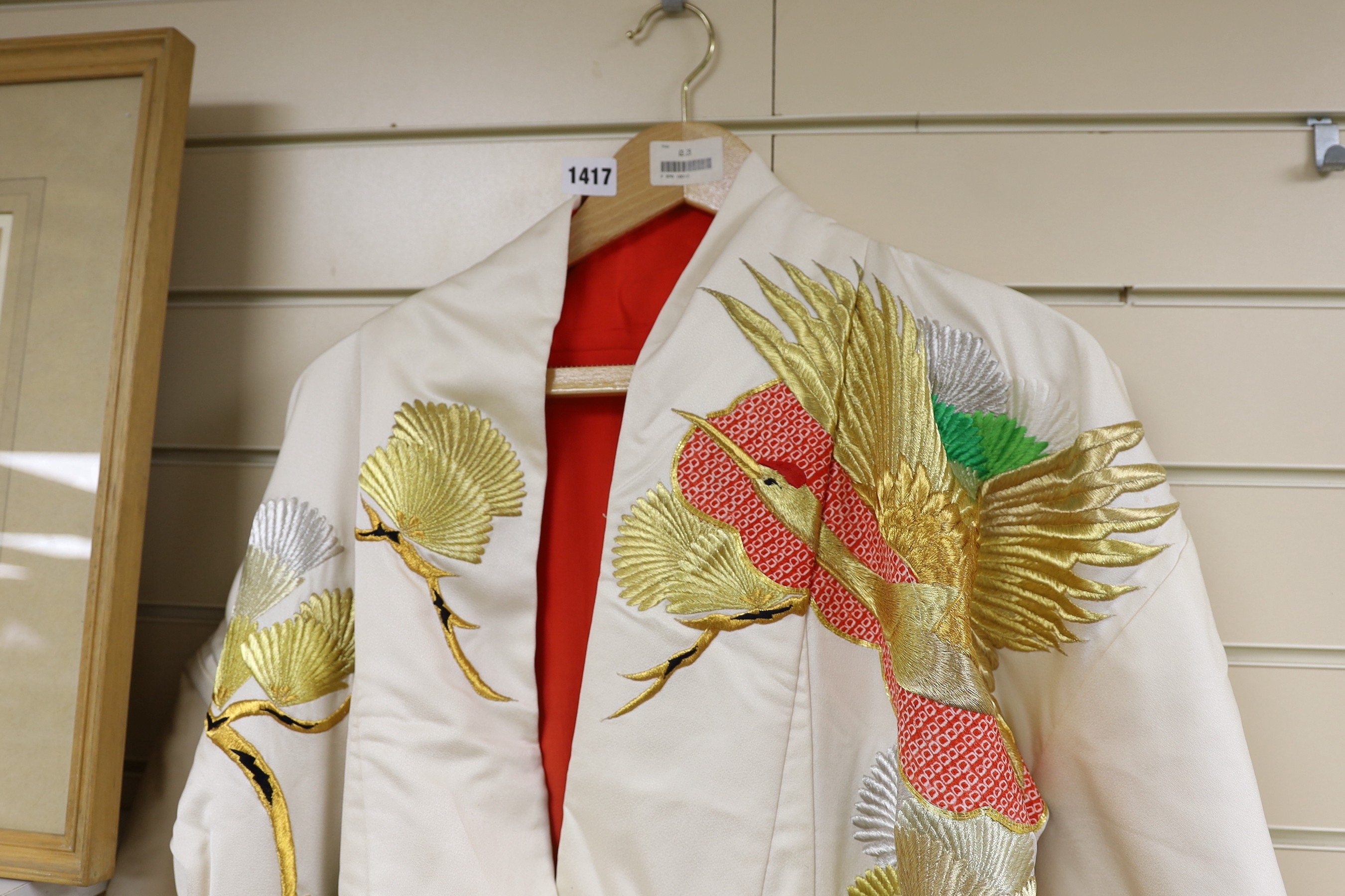 A Japanese cream ground ceremonial kimono, embroidered with coloured silks and metallic embroidery, in an all over design, with flame red silk lining